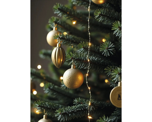 Nahaufnahme eines grünen Weihnachtsbaums mit verschiedenen goldenen Ornamenten und einer leuchtenden Lichterkette.