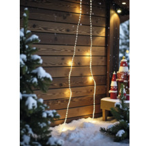 Warmweisse LED-Lichterketten an einer hölzernen Wand in einer verschneiten Szene mit Tannenbäumen und Weihnachtsdekoration.
