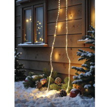 Warmweiße LED-Lichterkette an einer Holzwand mit verschneiten Tannenzweigen und Zapfen im Vordergrund.