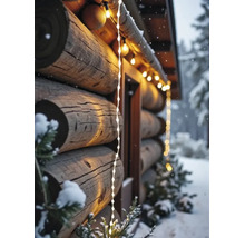 Aussenbeleuchtung an einem Blockhaus mit warmweissen Lichterketten und winterlicher Dekoration im Schnee.