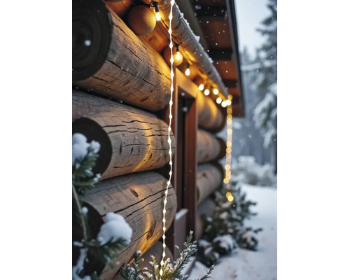 Aussenbeleuchtung an einem Blockhaus mit warmweissen Lichterketten und winterlicher Dekoration im Schnee.