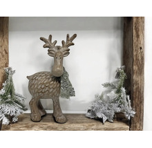 Dekorative Rentierfigur mit Schal und künstlichen Tannenbäumen auf einem Holzregal.