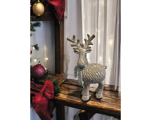 Dekorative Rentier-Figur mit glitzerndem Schal in einer weihnachtlichen Umgebung auf einer Holzoberfläche.