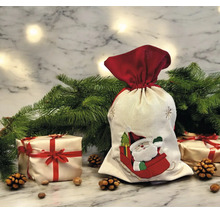 Weihnachts-Geschenksack aus Stoff mit Weihnachtsmann-Motiv in einer festlichen Szene mit Tannenzweigen, Geschenken und Tannenzapfen.