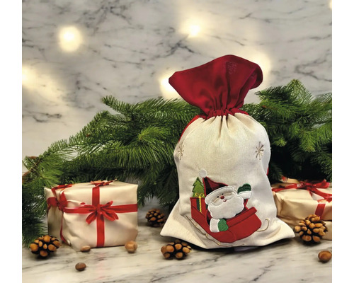 Weihnachts-Geschenksack aus Stoff mit Weihnachtsmann-Motiv in einer festlichen Szene mit Tannenzweigen, Geschenken und Tannenzapfen.