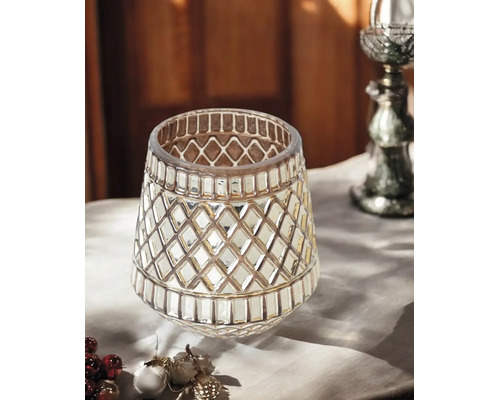 Dekoratives Windlicht aus Glas mit einem geometrischen Rautenmuster auf einem Tisch.