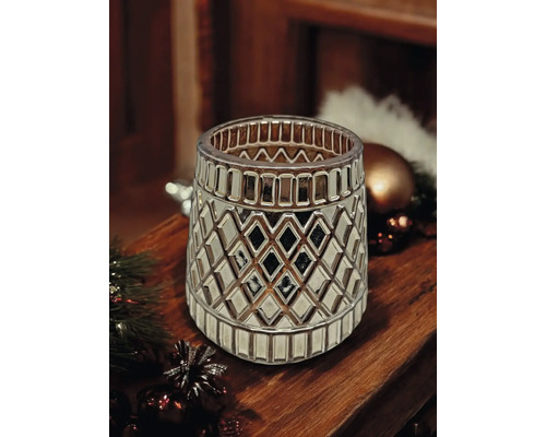 Dekoratives Windlicht aus Glas mit geometrischem Rautenmuster und metallischem Glanz auf einer Holzoberfläche mit Weihnachtsdekoration.