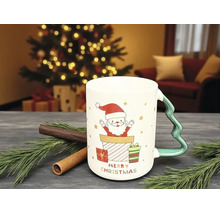 Weihnachtstasse mit Weihnachtsmann-Motiv, Geschenken und Henkel in Tannenbaumform auf einem Tisch mit Tannenzweigen und Zimtstangen.