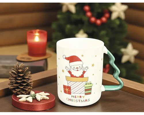 Weiße Weihnachts-Keramiktasse mit Weihnachtsmann-Motiv und Henkel in Tannenbaum-Form auf einem Tablett mit Dekoration.