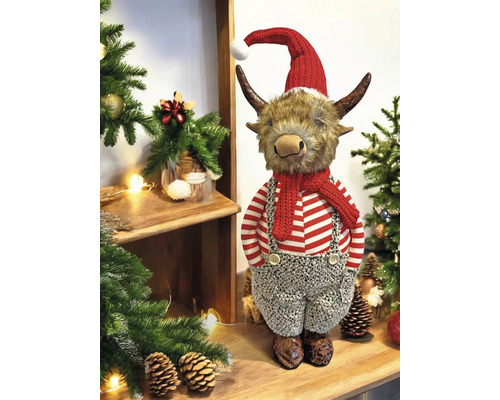 Dekorative Weihnachtsfigur Bulle mit Weihnachtsmütze, Schal und Latzhose, platziert auf Holz zwischen Tannengrün und Zapfen.