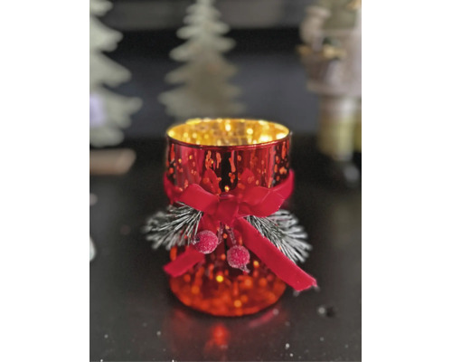 Festliches Windlicht aus Glas mit roter Schleife, beschneiten Tannenzweigen und Beeren für die Weihnachtsdekoration.