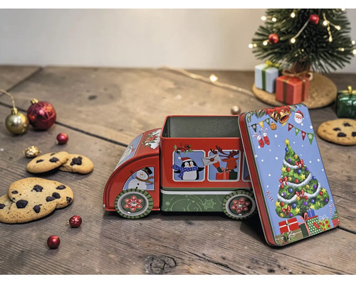 Weihnachts-Gebäckdose aus Metall in Form eines Lastwagens mit Motiven wie Tannenbaum und Schneemann auf einem Holztisch mit Keksen und Dekoration.