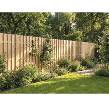 Haute clôture en bois composée de lattes verticales à têtes arrondies dans un jardin ensoleillé avec pelouse, fleurs et arbres.