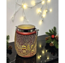 Rotes Weihnachts-LED-Windlicht mit winterlichem Dorf-Motiv, Seilgriff und Metallrand neben Tannenzweigen auf einer reflektierenden Oberfläche.