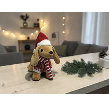 Plüschhund mit Weihnachtsmütze und rot-weiß gestreiftem Pullover auf einem hellen Holztisch mit Tannenzweig und Tannenzapfen.