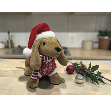 Stofftier Dackel mit Weihnachtsmütze und Strickpullover auf einem Holztisch neben Weihnachtsdekoration.