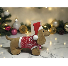 Plüschtier Dackel mit rotem Weihnachtspullover und Weihnachtsmütze vor weihnachtlicher Dekoration.