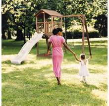 Aire de jeux en bois avec toboggan, balançoire, cabane et bac à sable dans un jardin lumineux avec une femme et un enfant.