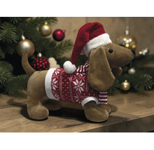 Plüsch-Dackel mit Weihnachtsmütze und rotem Weihnachtspullover vor einem Weihnachtsbaum.