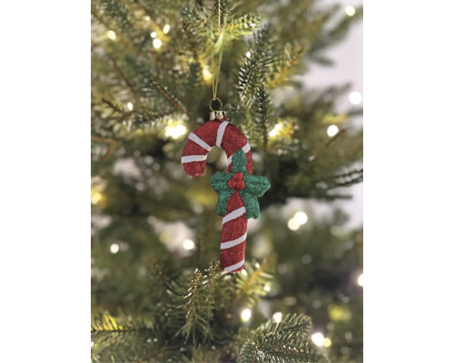 Weihnachtsbaumanhänger Zuckerstange rot und weiß mit Glitzer, dekoriert mit grüner Stechpalme, hängend an einem Weihnachtsbaum.