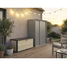 Aussenbereich mit moderner Aufbewahrungsbox in Holzoptik und grauem Metall-Gartenschrank auf einer Holzterrasse mit Lichterkette und Sitzbereich.