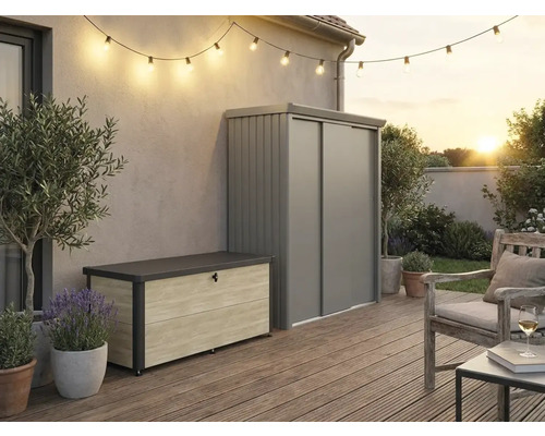Aussenbereich mit moderner Aufbewahrungsbox in Holzoptik und grauem Metall-Gartenschrank auf einer Holzterrasse mit Lichterkette und Sitzbereich.