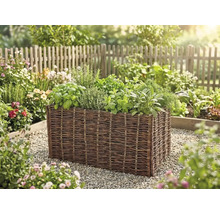 Hochbeet aus geflochtener Weide mit verschiedenen Kräutern wie Basilikum und Minze in einem hellen Garten.
