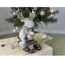 Weihnachtsdekoration mit zwei Elchfiguren, groß und klein, sitzend auf einem Holzschlitten vor einem Weihnachtsbaum.
