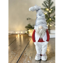 Stehende Weihnachtsfigur Wichtel mit grauer Zipfelmütze, weißem Bart, rotem Pullover und weißer Hose auf einem Holzfußboden.