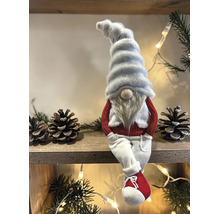 Weihnachts-Wichtel Figur mit weißer Zipfelmütze, langem Bart, rotem Pullover und weißer Hose sitzend auf einem Holzregal.