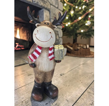 Weihnachtsdekoration Rentier-Figur mit gestreiftem Schal und Geschenk vor Kamin und Tannenbaum.
