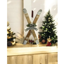 Dekorative Holzskier in Form eines X mit Welcome Schild zwischen zwei kleinen beleuchteten Weihnachtsbäumen auf einer hellen Holzfläche.