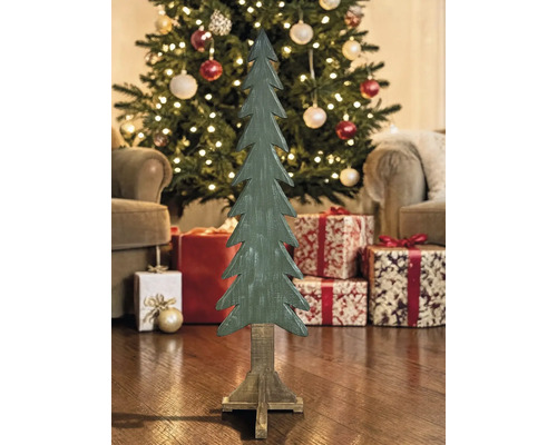 Dekorativer Holz-Tannenbaum auf Standfuß in weihnachtlicher Umgebung mit beleuchtetem Baum und Geschenken.