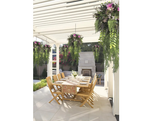 Außenessbereich unter einer weißen Pergola mit Holztisch, Holzstühlen, hängenden Pflanzen und einem Steinkamin auf einer gefliesten Terrasse.