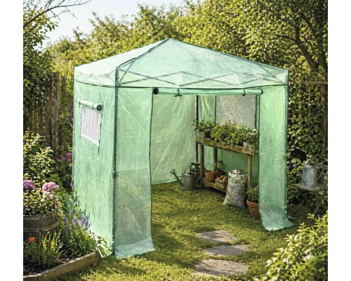 Begehbares Foliengewächshaus im Garten mit Holzregal, Pflanzen in Töpfen, Gießkanne und Erdsack auf dem Rasen.