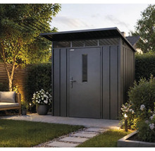 Abri de jardin moderne en métal avec toit en appentis, porte avec fenêtre et impostes dans un jardin aménagé avec des dalles.