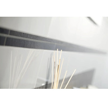 Gros plan de carreaux de mur blancs brillants avec une frise foncée et texturée.