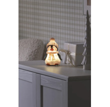 Figurine décorative LED pingouin avec bonnet et écharpe sur un buffet à côté d'un cadeau et d'un arbre de décoration.