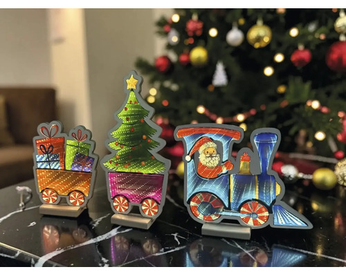 Train de Noël décoratif avec locomotive, Père Noël, sapin et wagons de cadeaux sur une table devant un sapin de Noël illuminé.
