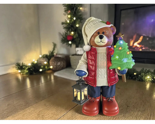 Ours de décoration de Noël avec lanterne et sapin illuminé dans un salon lumineux devant une cheminée.
