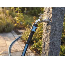 Textilschlauch mit for_q Logo an einem Aussenwasserhahn an einer Steinsäule im Garten.