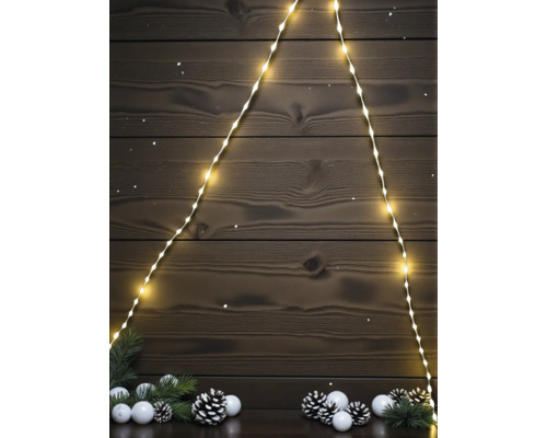 LED-Lichterkette in Form eines Weihnachtsbaums vor dunkler Holzwand mit Tannenzweigen, Kugeln und Tannenzapfen.