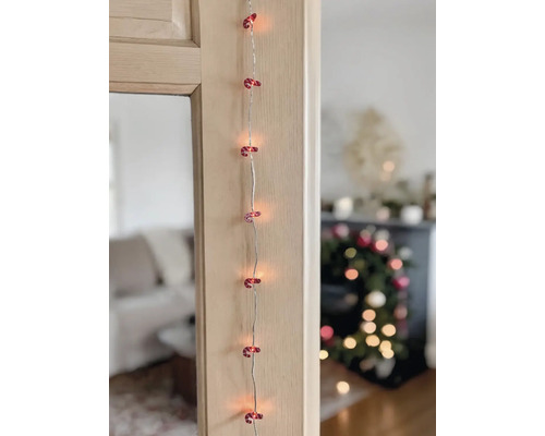 LED-Lichterkette mit rot-weißen Zuckerstangen-Motiven an einem Holzrahmen in weihnachtlicher Umgebung.