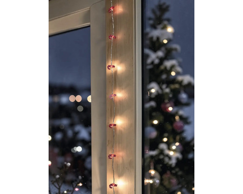LED-Lichterkette mit Zuckerstangen-Motiven vertikal an einem Holzrahmen angebracht, im Hintergrund ein geschmückter Tannenbaum.