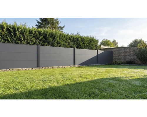 Clôture pare-vue moderne composée de panneaux horizontaux gris anthracite dans un jardin avec pelouse et haie.