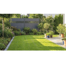 Clôture de protection visuelle moderne de couleur anthracite avec motif découpé décoratif dans un jardin avec pelouse et terrasse.