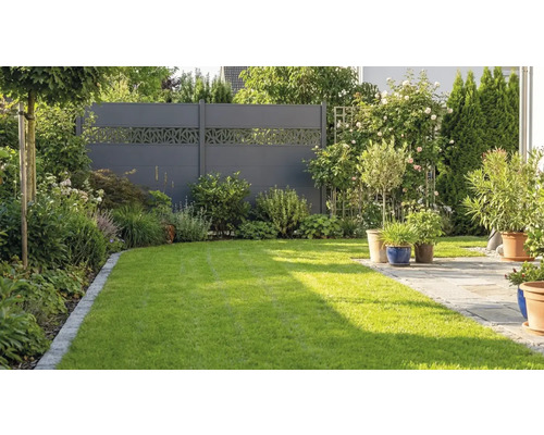 Clôture de protection visuelle moderne de couleur anthracite avec motif découpé décoratif dans un jardin avec pelouse et terrasse.