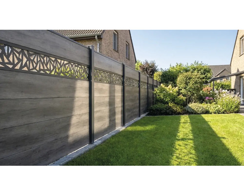 Clôture de jardin moderne en planches composites grises avec bande décorative ajourée et poteaux métalliques dans un jardin soigné.