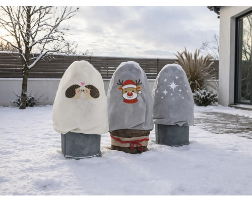Drei Winterschutz-Vlieshauben mit Igel-, Rentier- und Sternmotiven schützen Pflanzen in einem hellen, verschneiten Garten vor Frost.