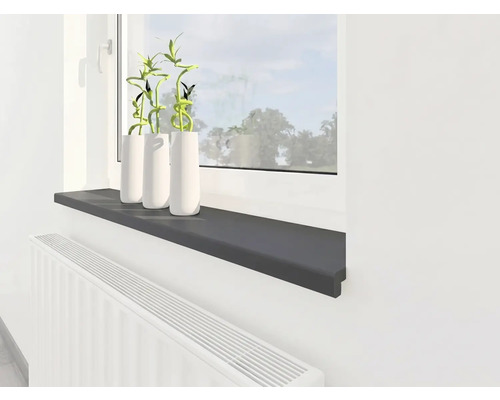 Moderne Innenfensterbank in Anthrazit, montiert über einem weißen Heizkörper unter einem Fenster mit Dekopflanzen.